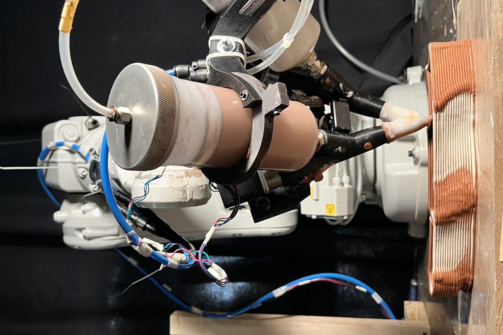 Robotic arm depositing mortar in the multi-material printing process