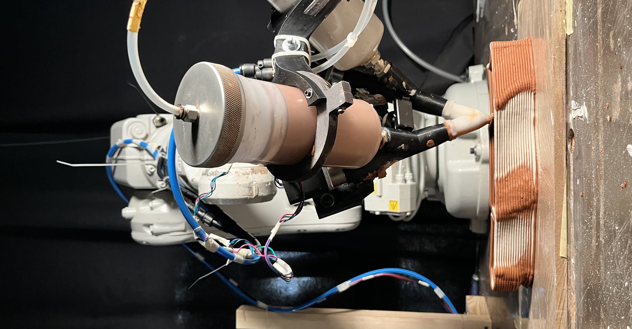 Robotic arm depositing mortar in the multi-material printing process