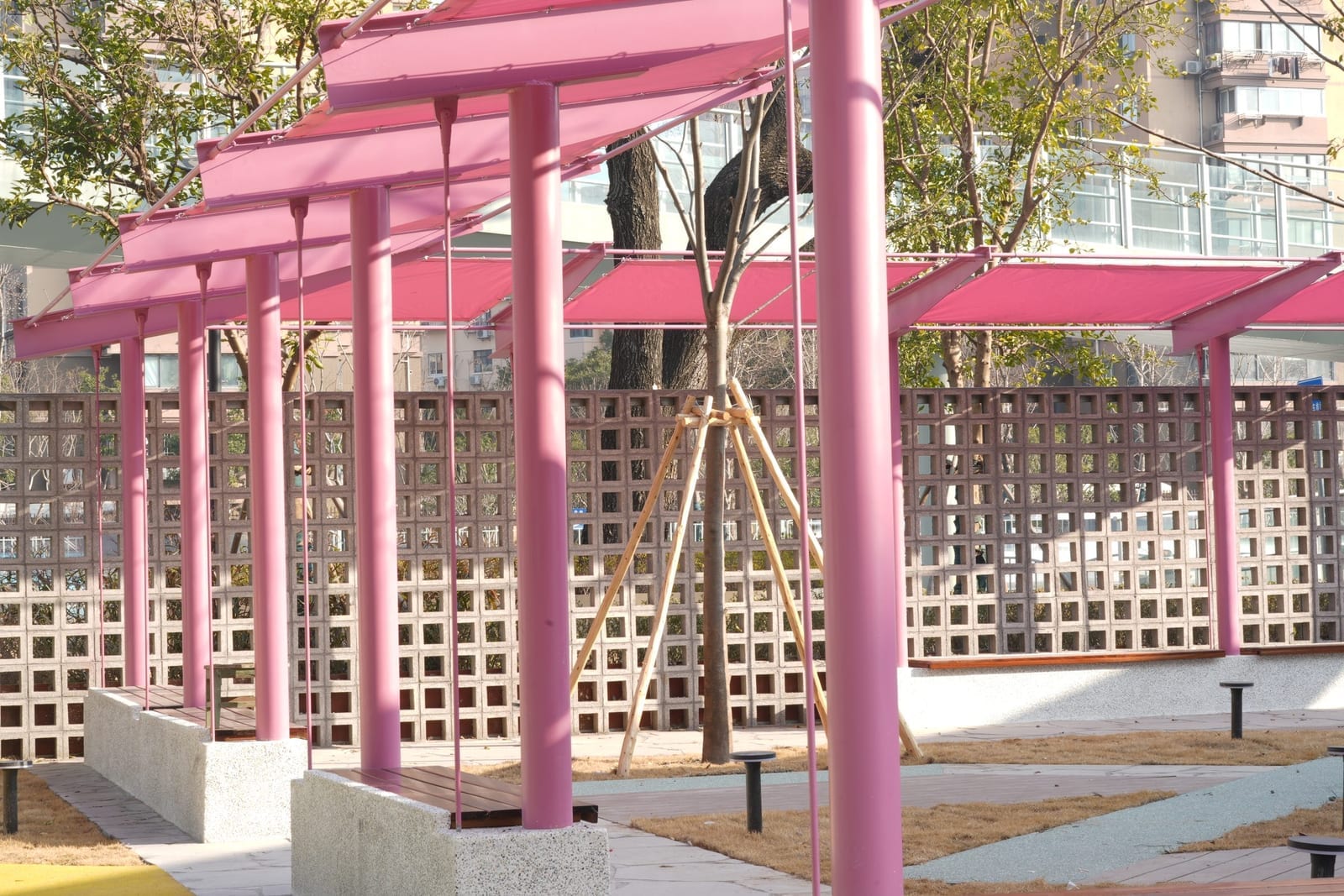 The pink steel pergola in front of the breeze-block screen wall