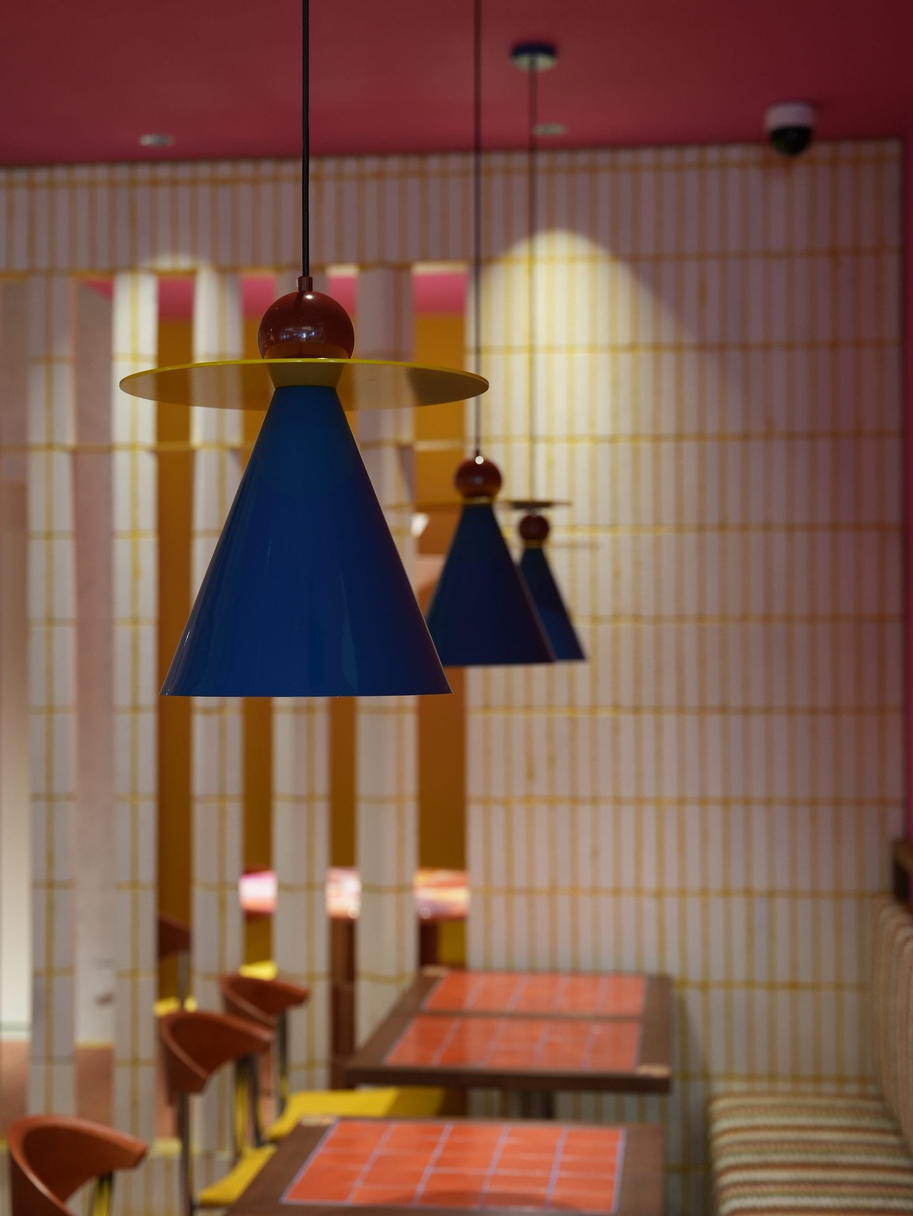 Cobalt-blue conical pendants over a pink-tiled nook