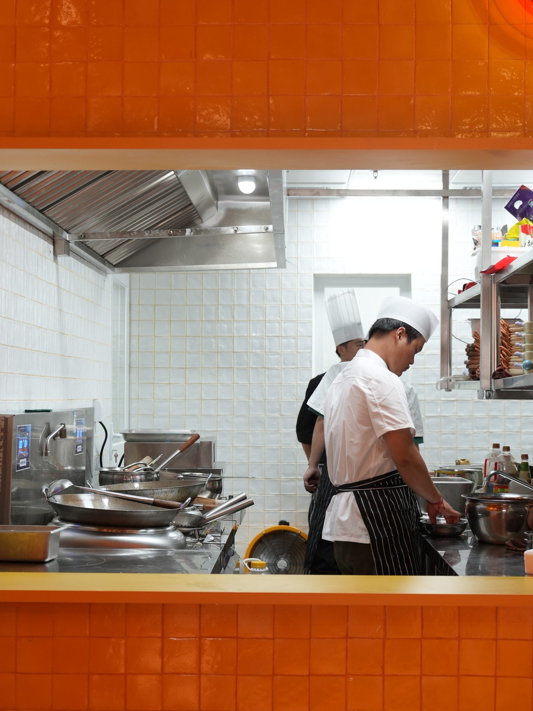 Chefs at work behind the orange-tiled kitchen pass