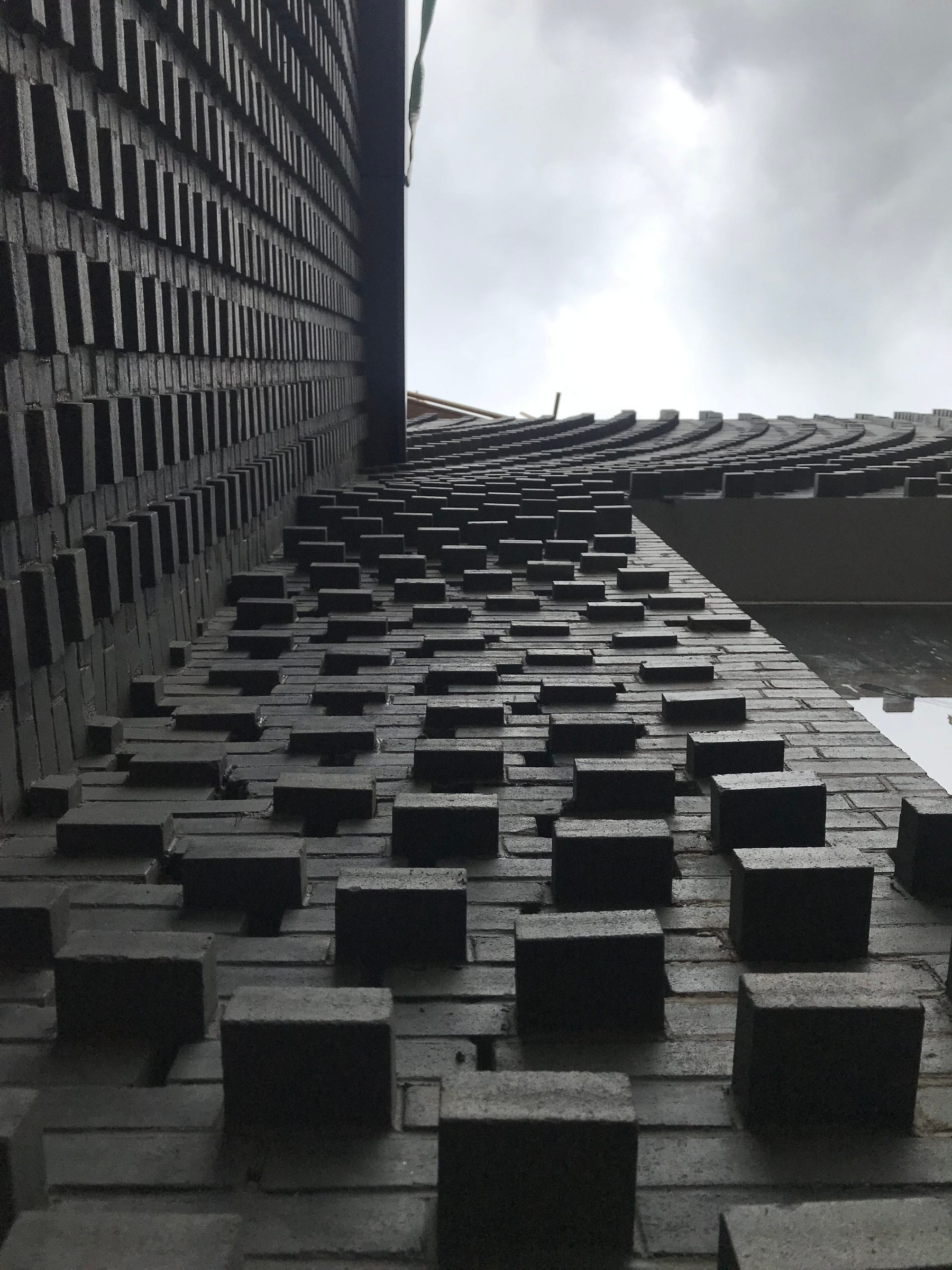 Raking view along the stacked-brick facade — each course offset by the robotic laying pattern