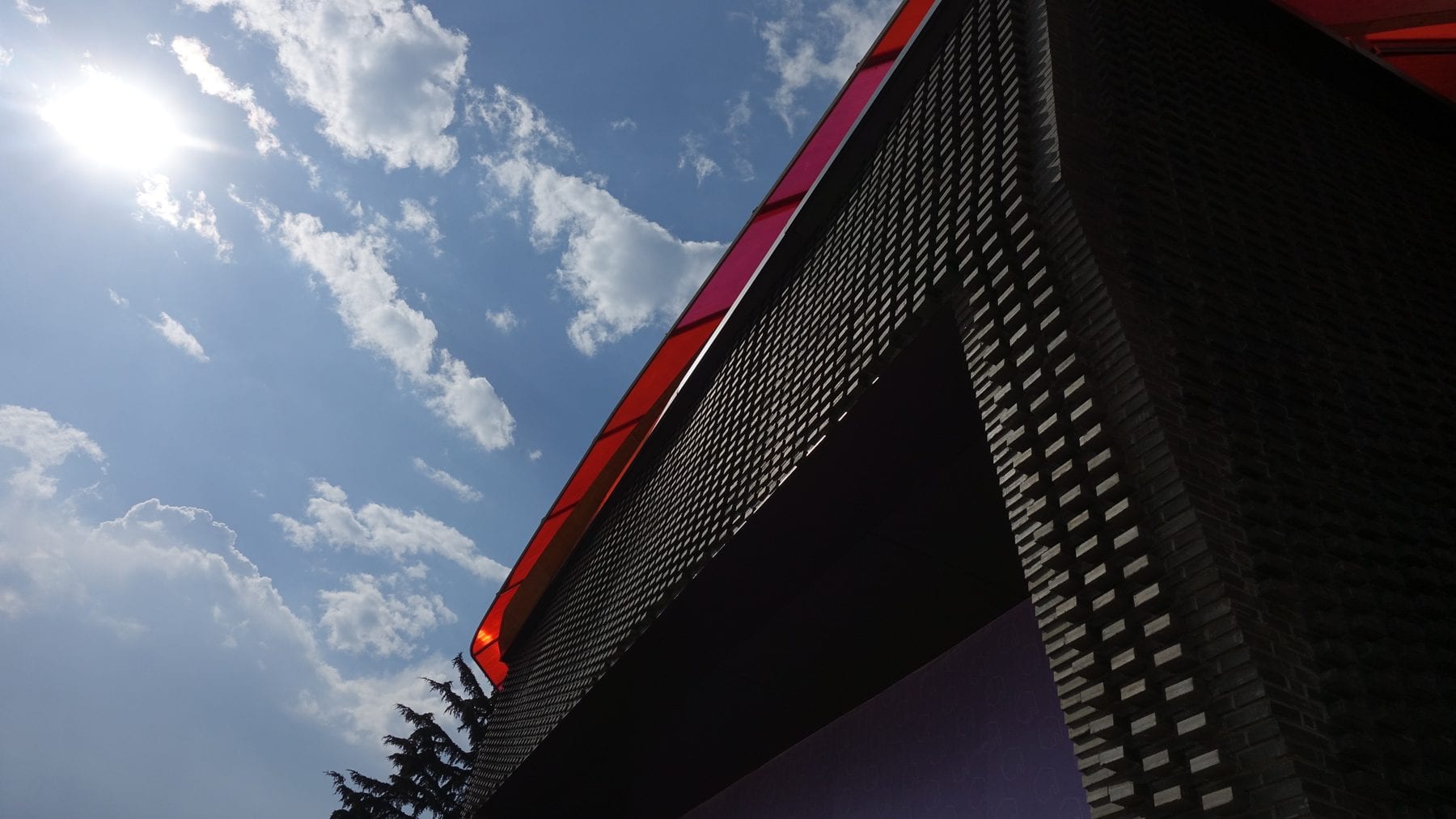 Visitor center during construction — brick base walls and the red steel canopy frame