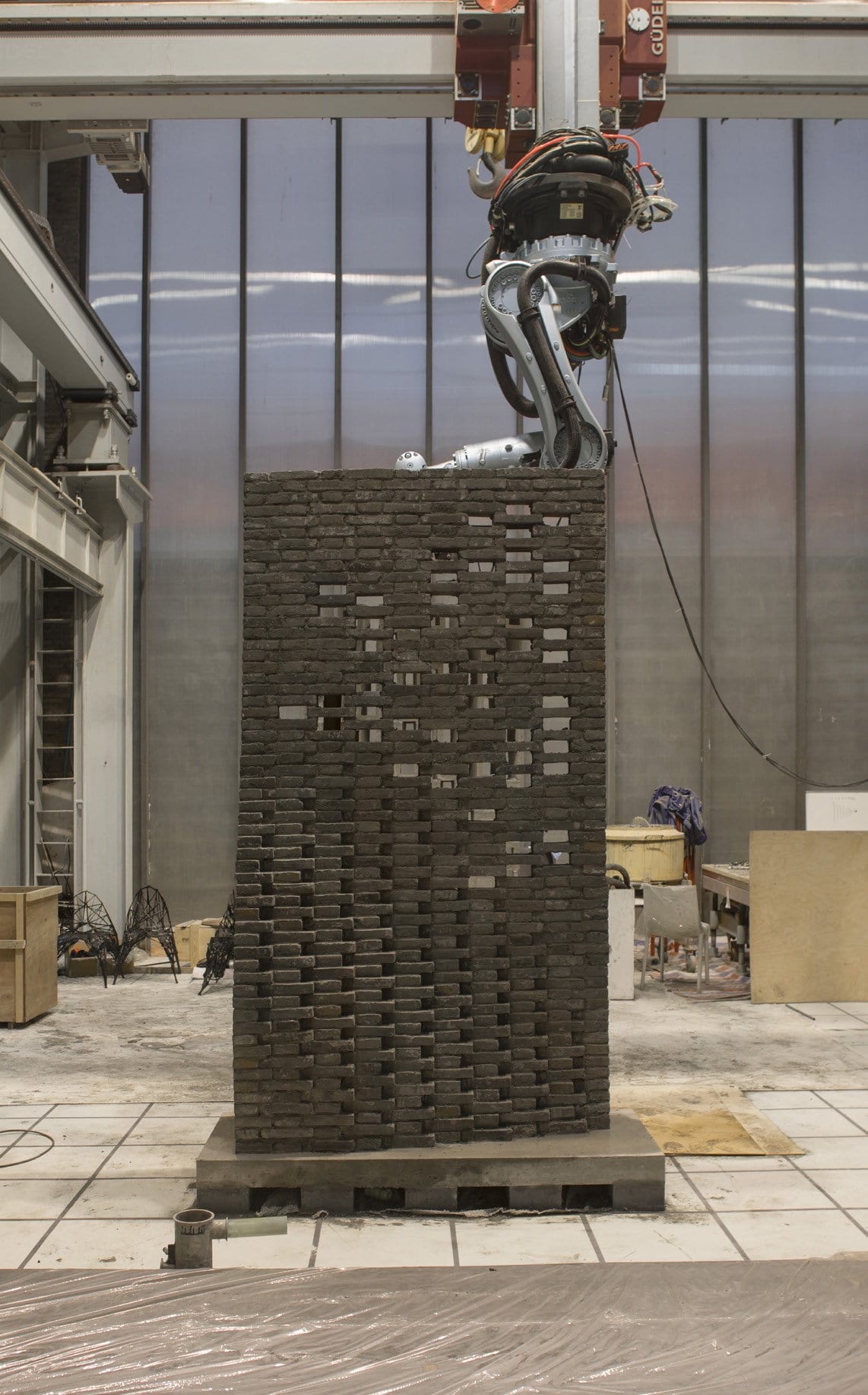Robot arm building the curved brick wall in the fabrication hall