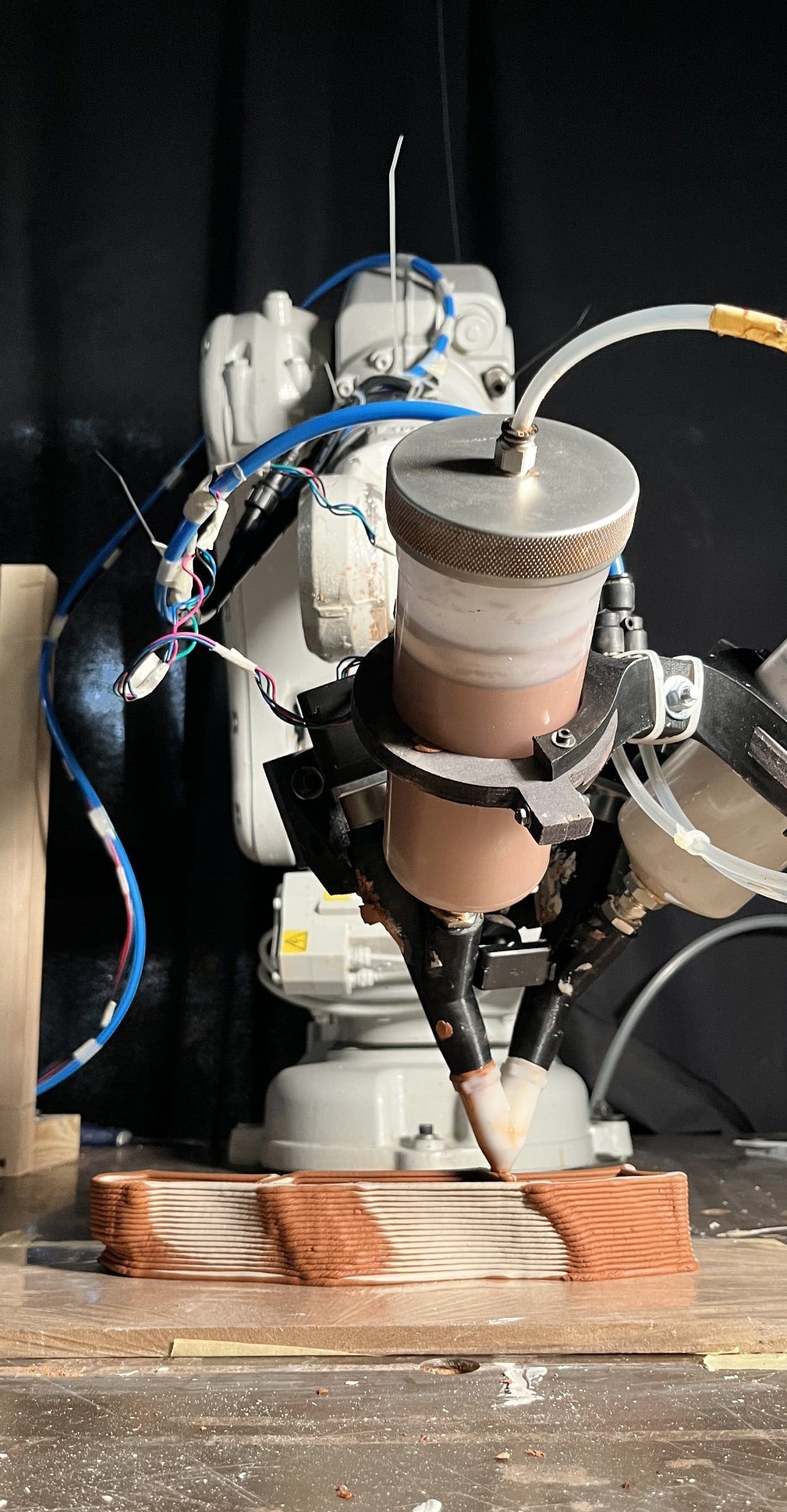 Robotic arm depositing mortar in the multi-material printing process