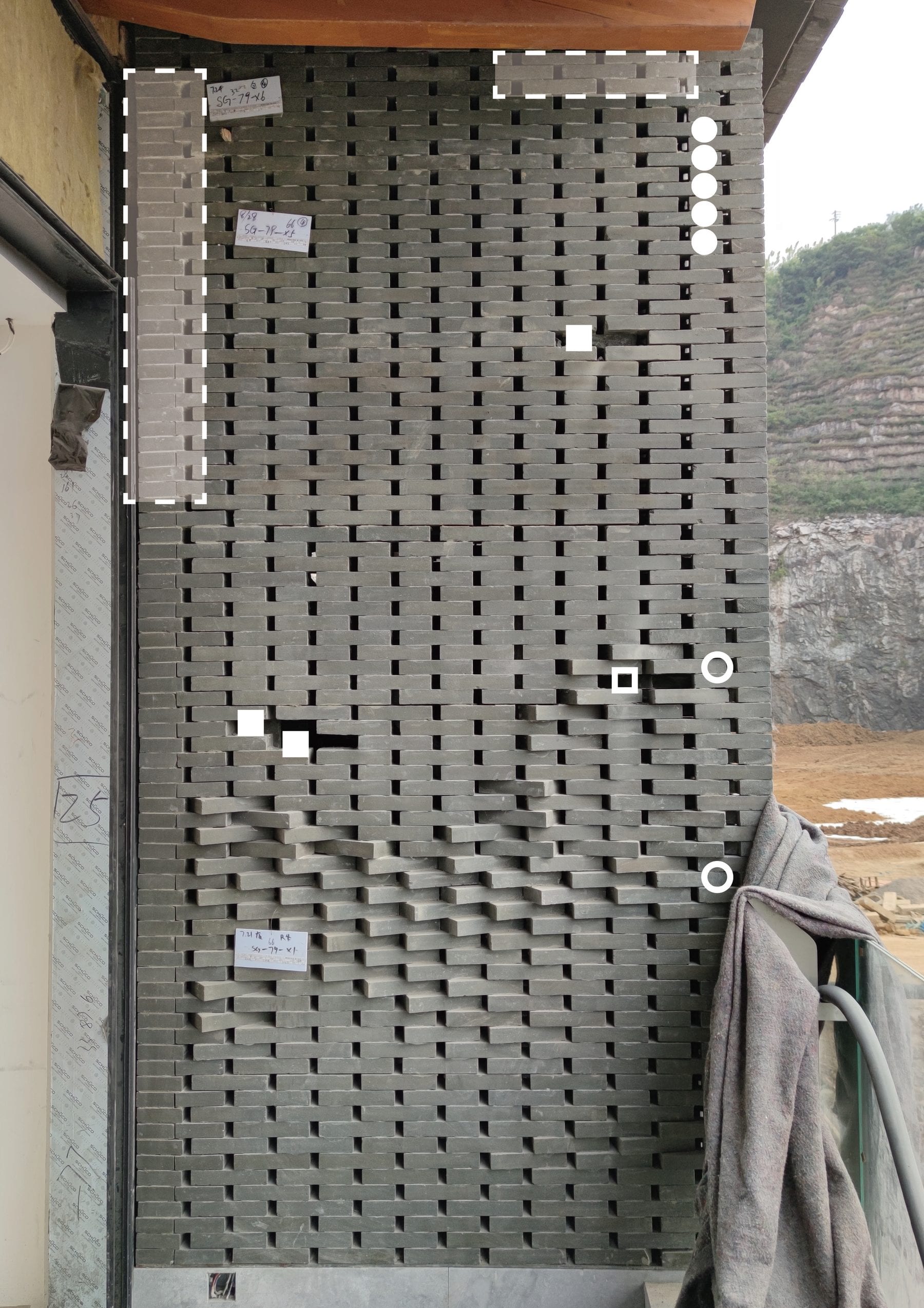 Full-height perforated brick wall at the south tower, inspection markers on individual bricks
