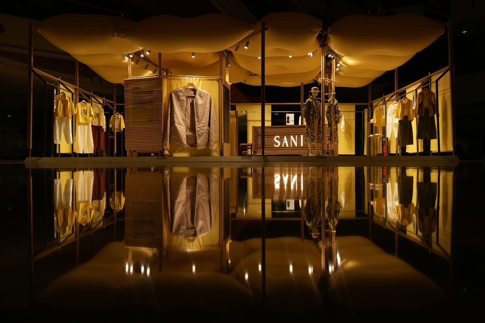 Inside the Lanxi Pavilion at night — glowing yellow inflatable pillows above the SANI retail bays