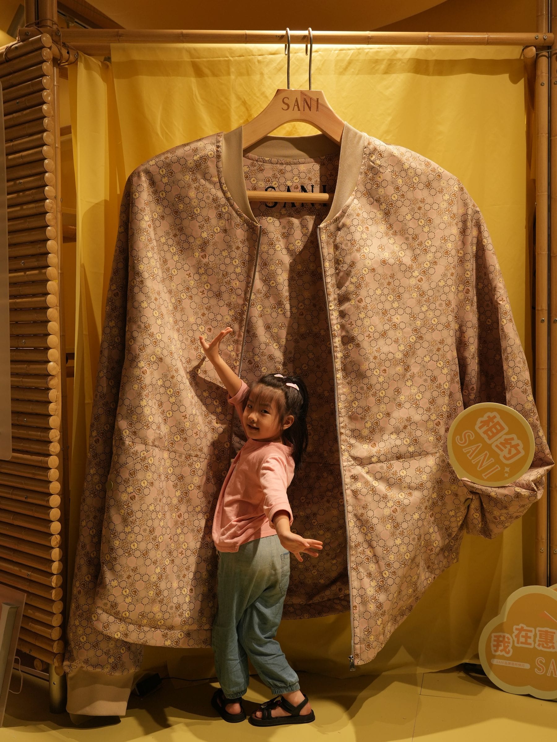 A child reaching towards a garment inside the yellow fabric enclosure