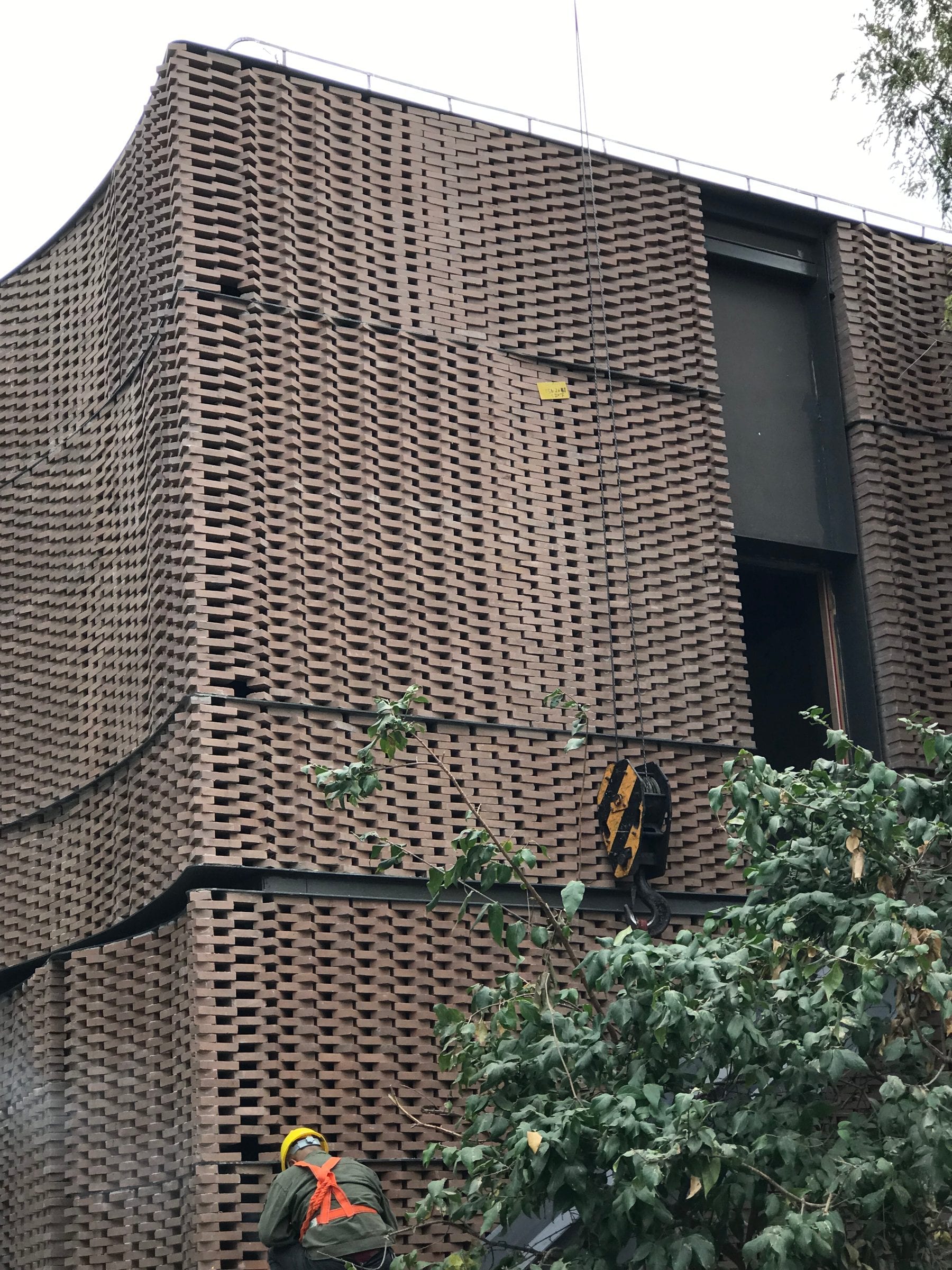 Woven brick facade mock-up against the existing trees on site