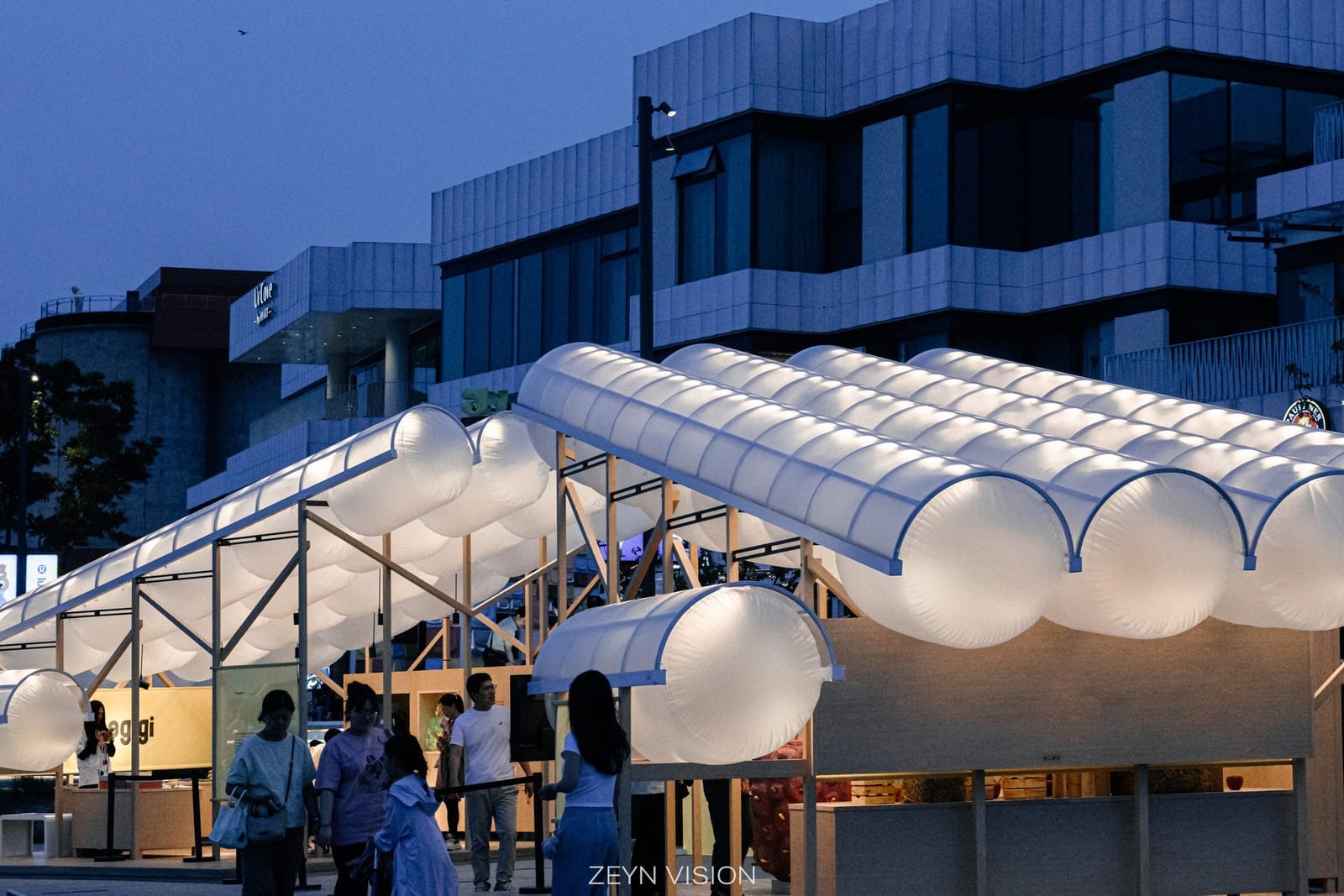The two hunogigi pavilions glowing at dusk with visitors gathering on the promenade