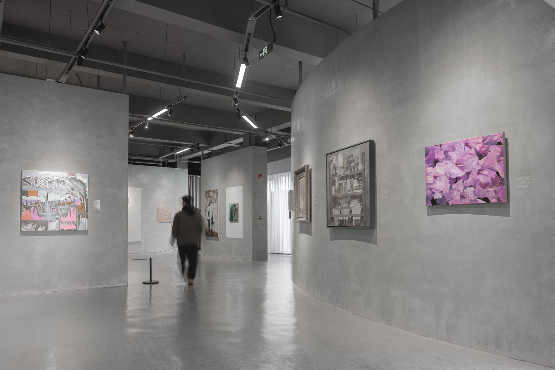 Curved concrete gallery walls, a visitor crossing the hall