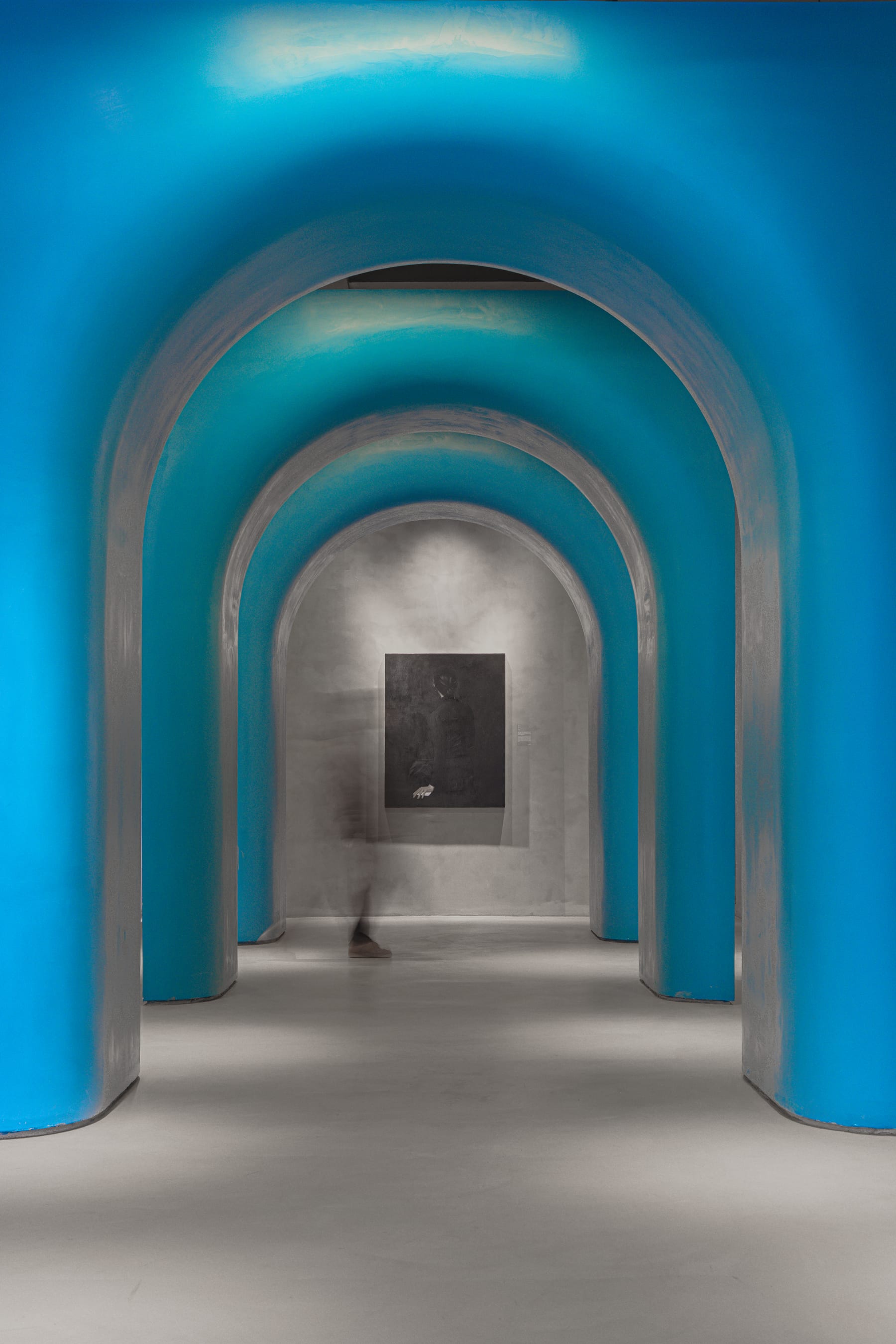 A reader drifting through the blue arched corridor, long exposure