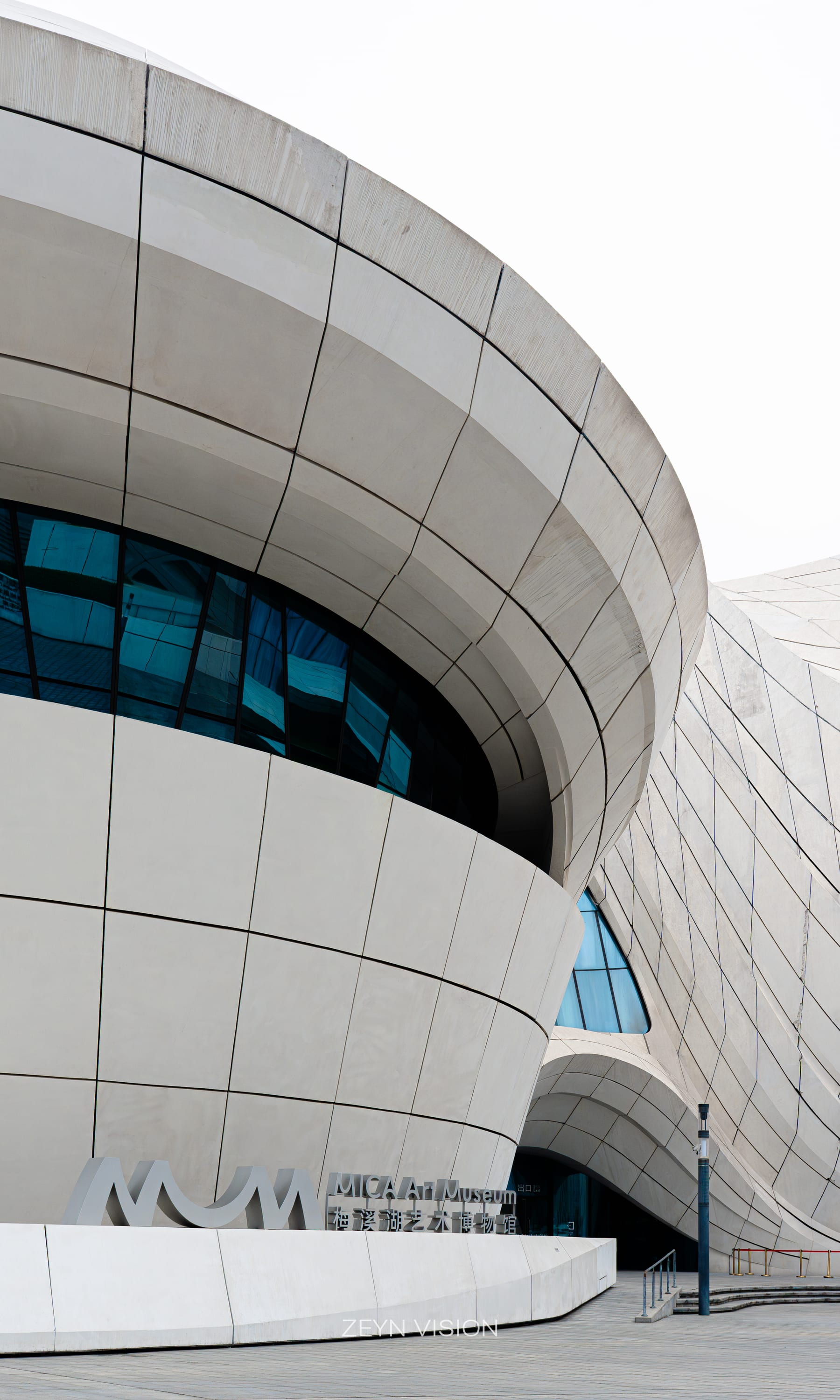 Curved white facade of the arts centre with a turquoise glass band