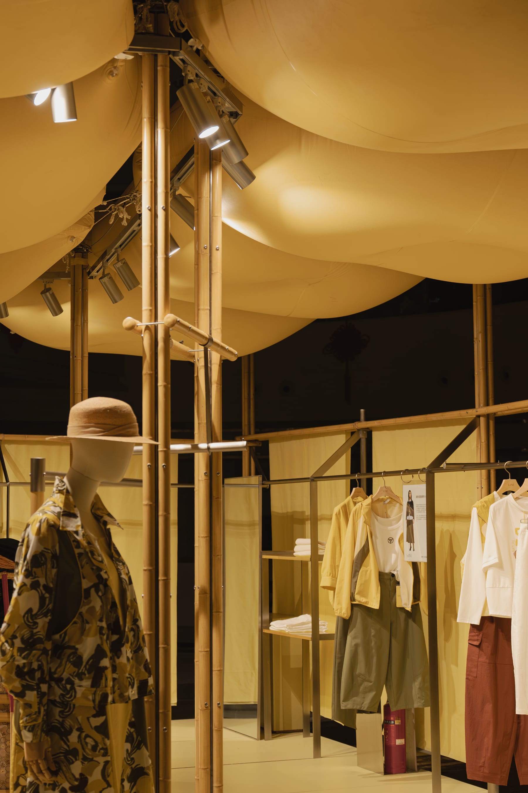 Mannequin in floral suit under the pillow canopy, columns and garment rails at night