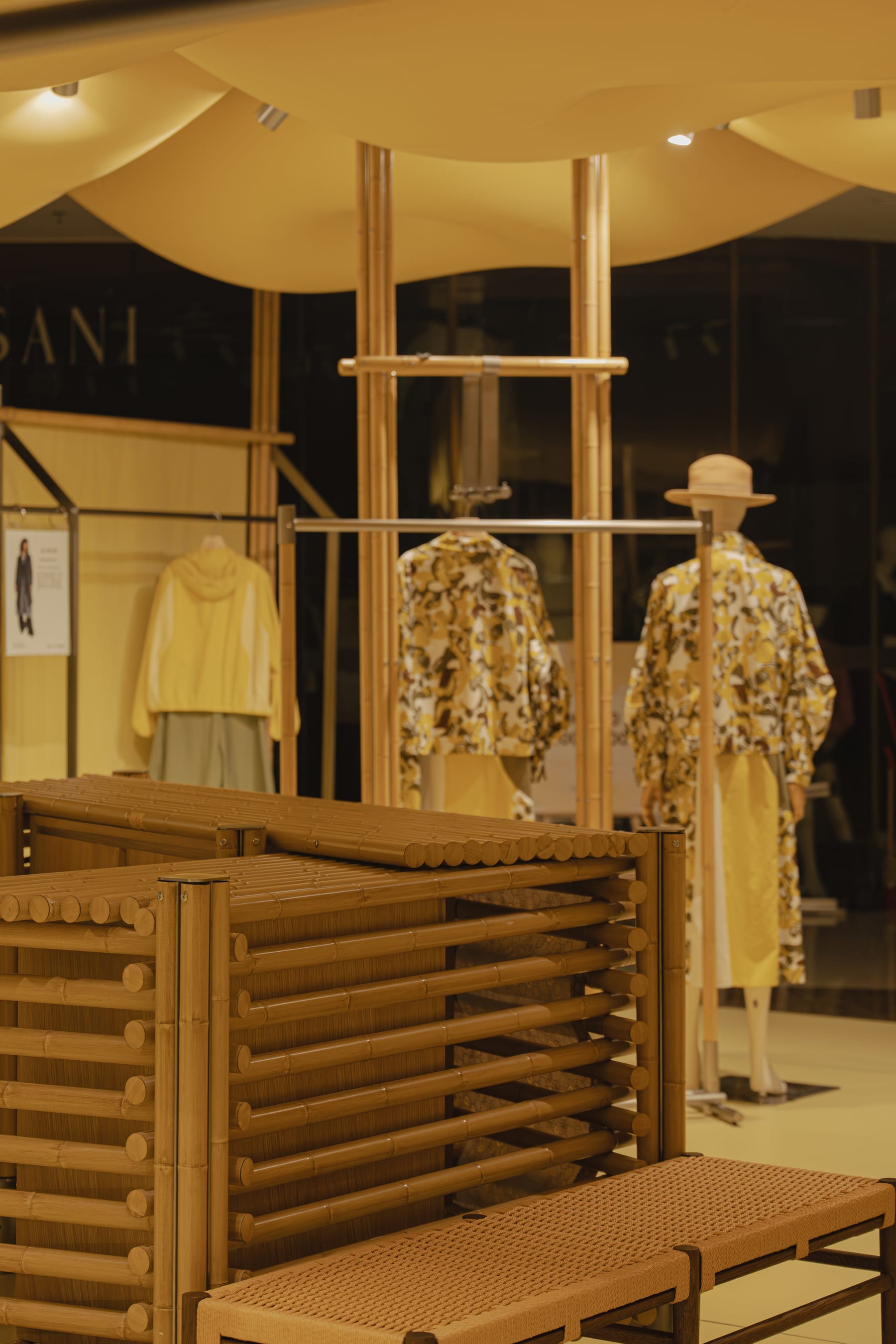 Bamboo-rod screen and woven bench with mannequins behind, night