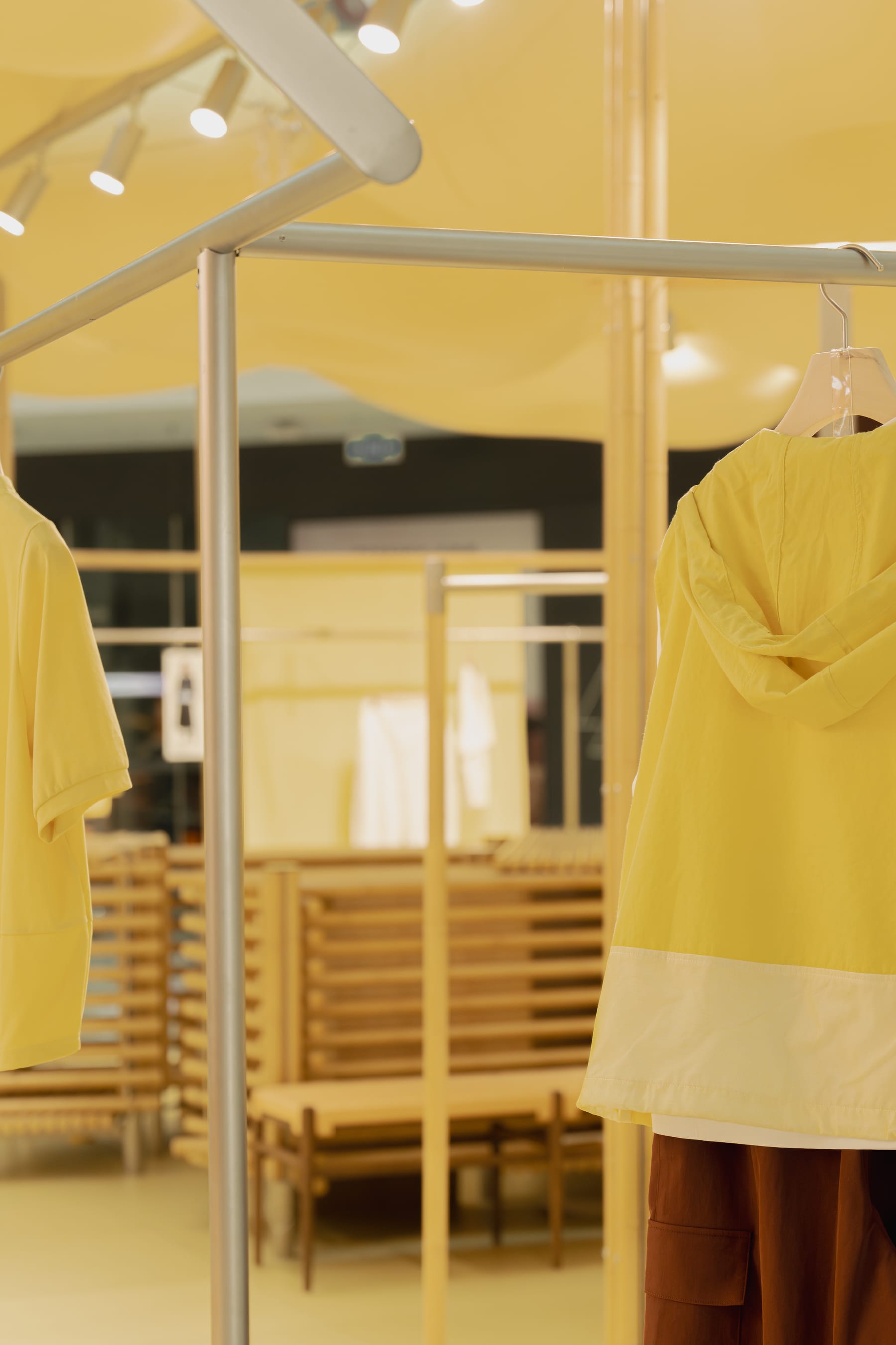 Garment rails and bench in the fitting bay, yellow collection pieces