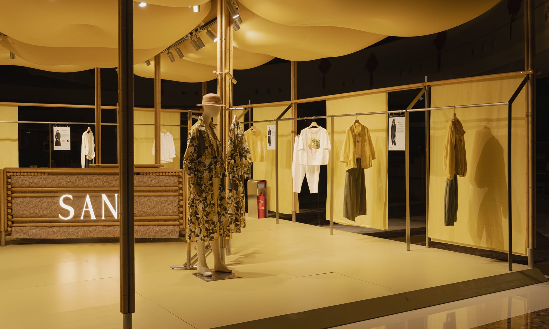 Night interior — SANI logo screen wall, mannequin and garment bays