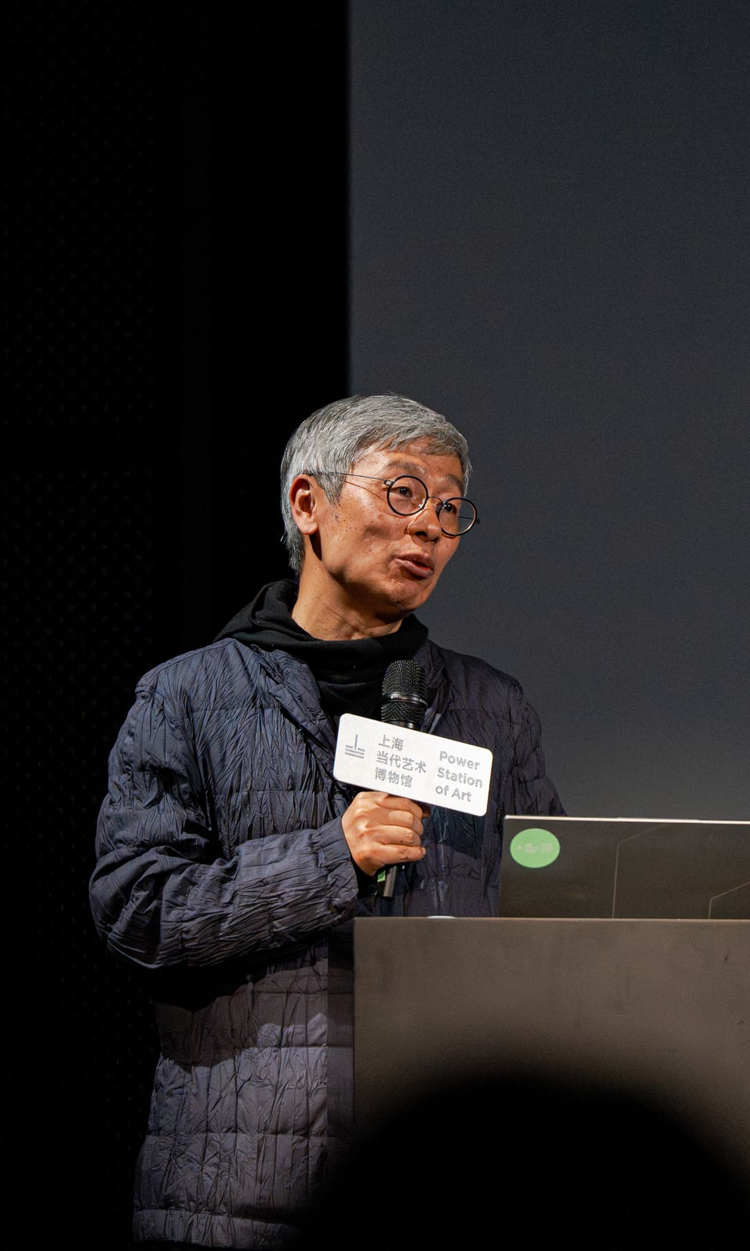 The lecturer standing in the dark auditorium