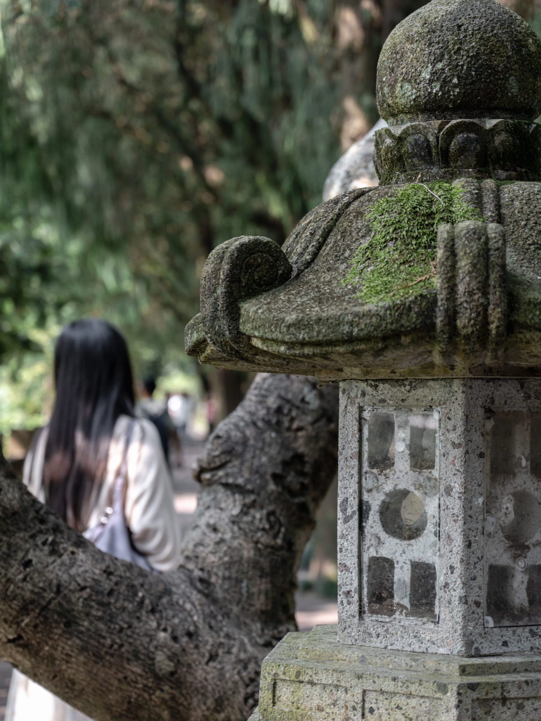 Moss-covered stone sculpture and a visitor at the temple