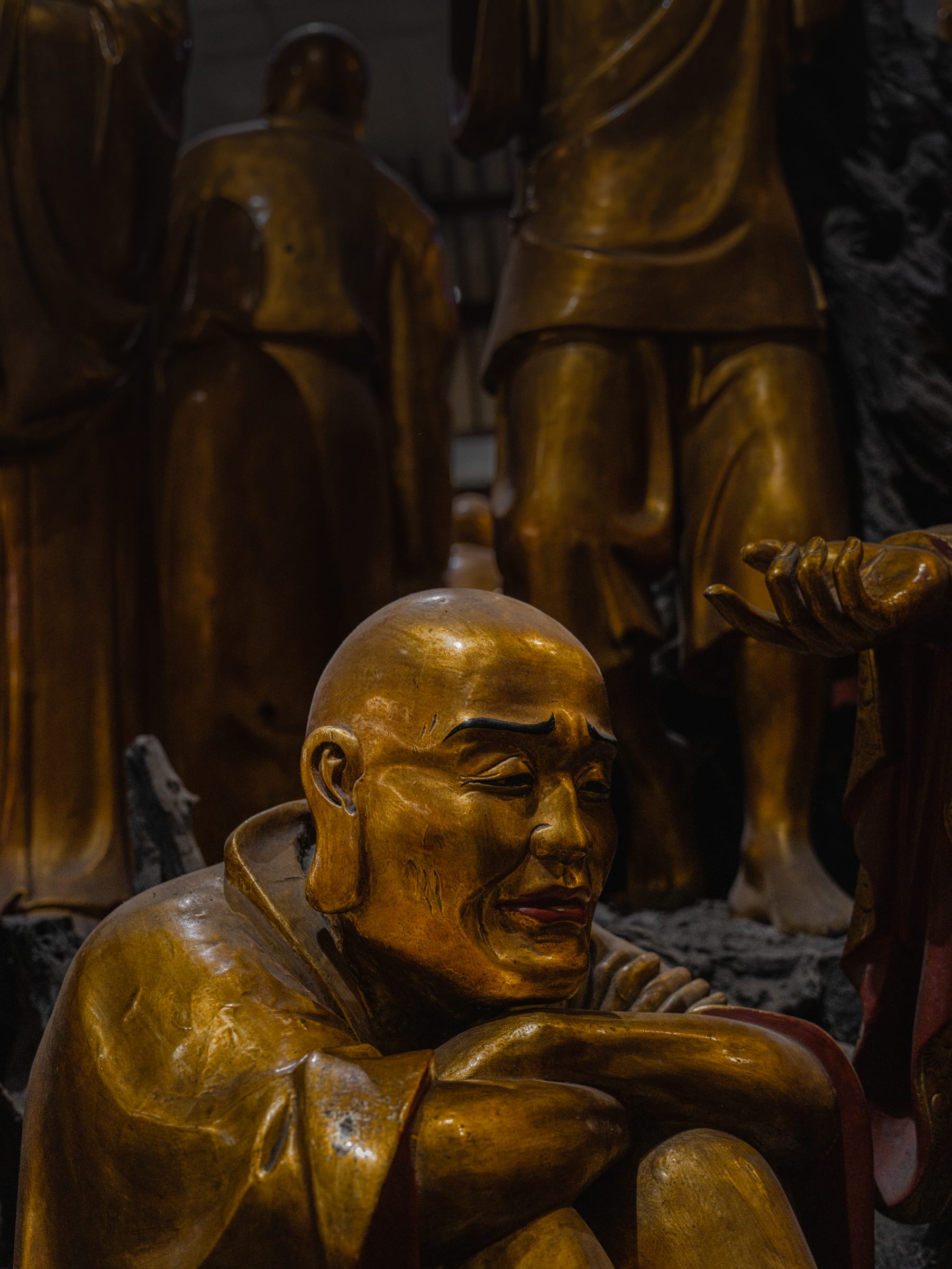 A smiling golden luohan among the crowd of statues