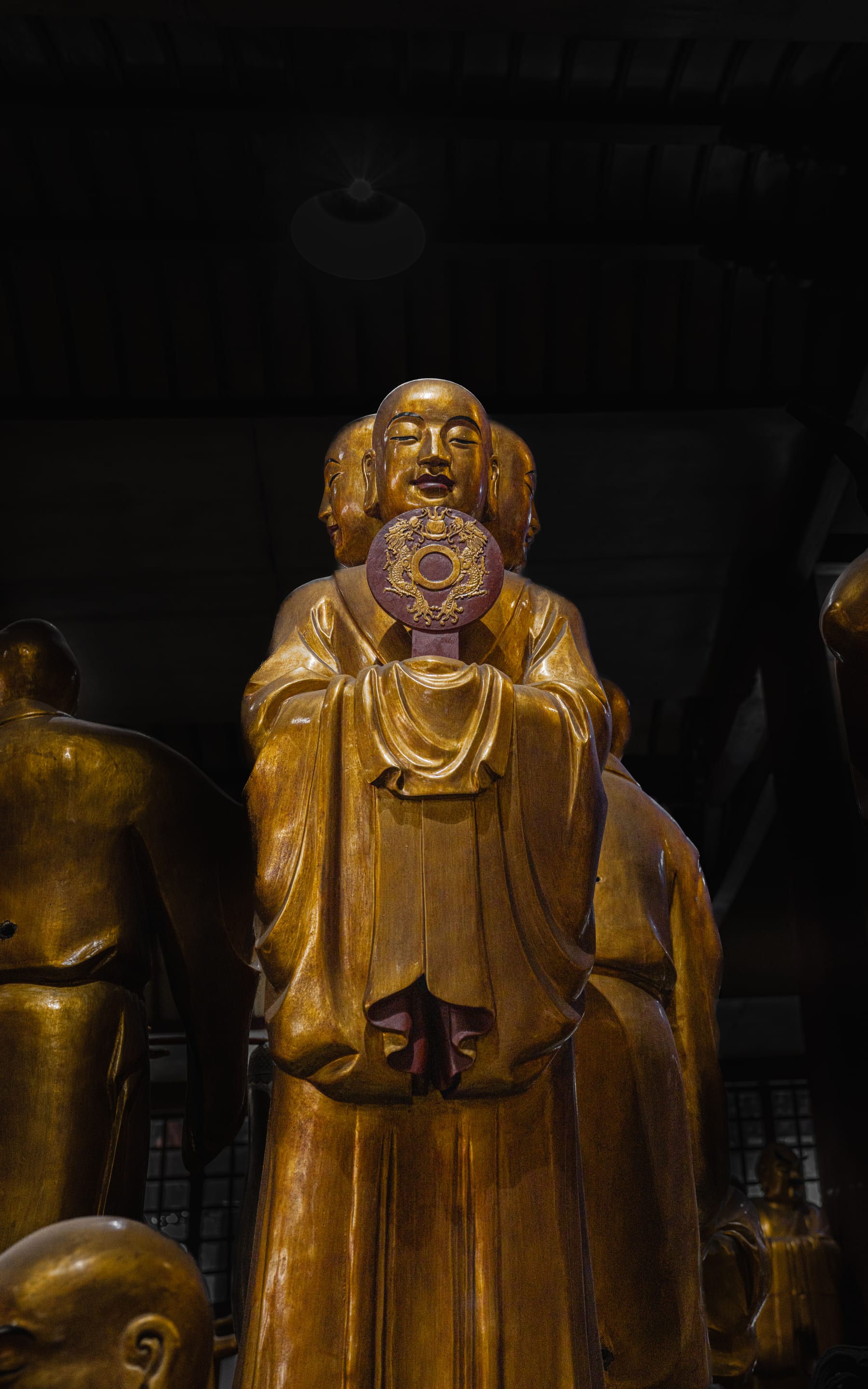 Rows of gilded luohan faces in low light