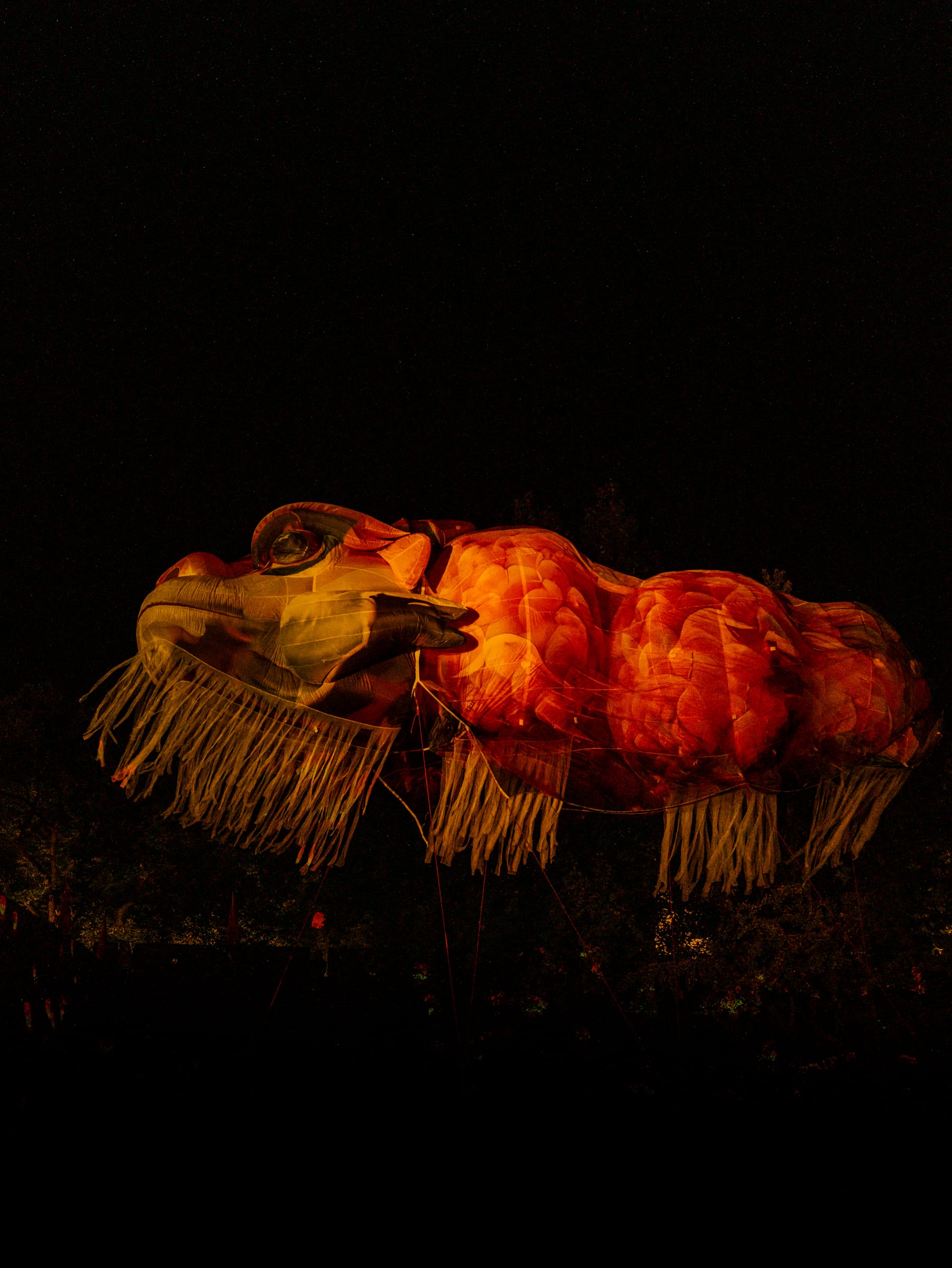 A sculpted beast glowing red in the night hall