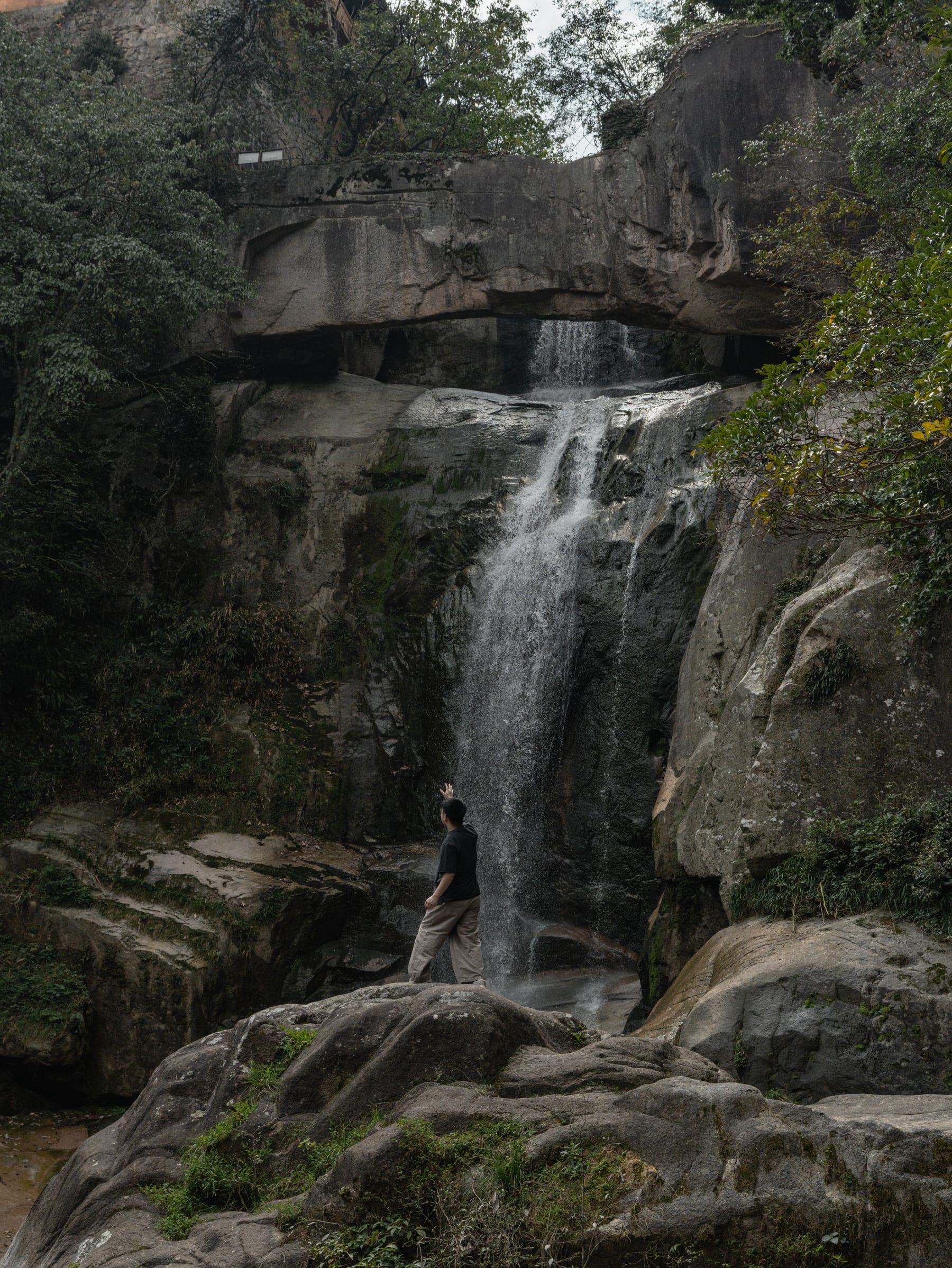 A visitor standing beneath the waterfall