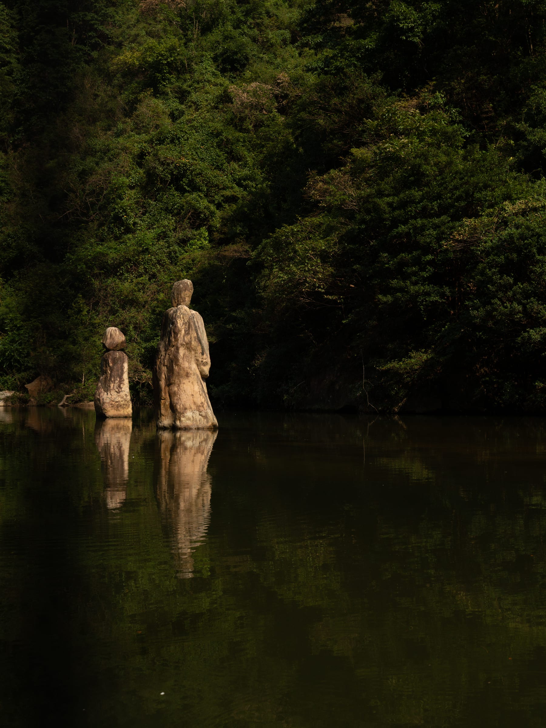 Stone figures standing in dark still water